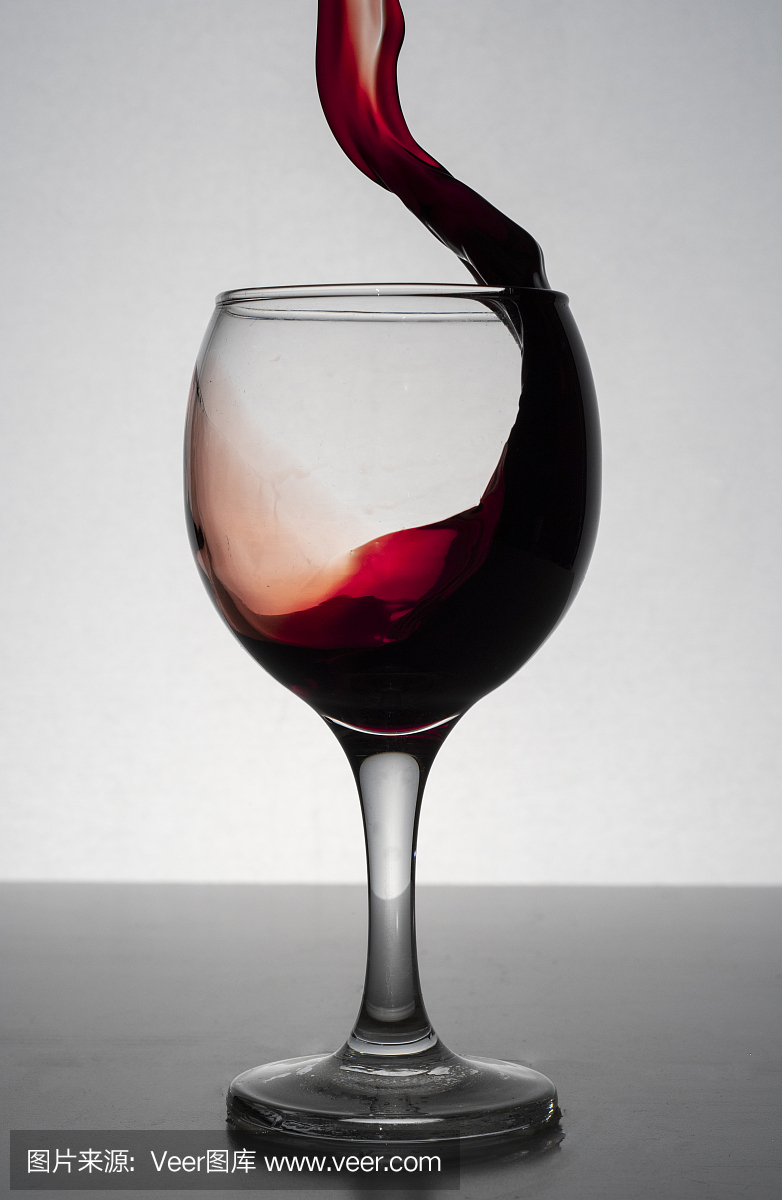 红酒从杯子里溅出来,孤立在白葡萄酒上